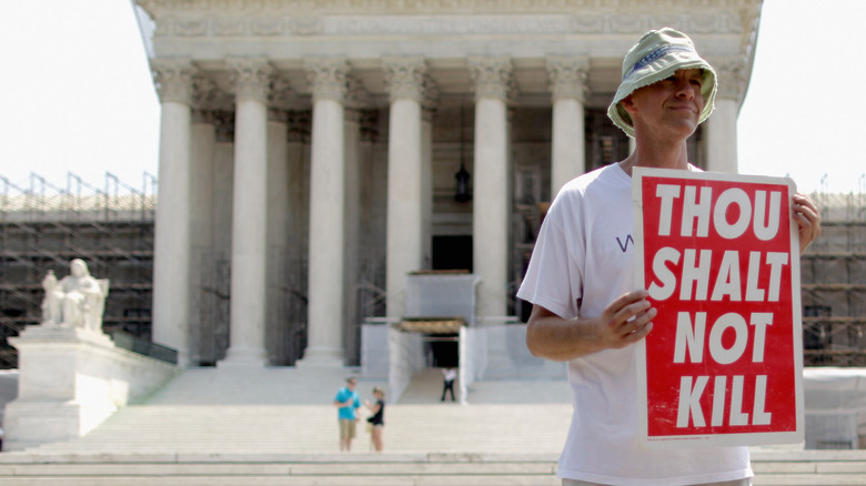 Protester holding a sign that says Thou Shalt Not Kill
