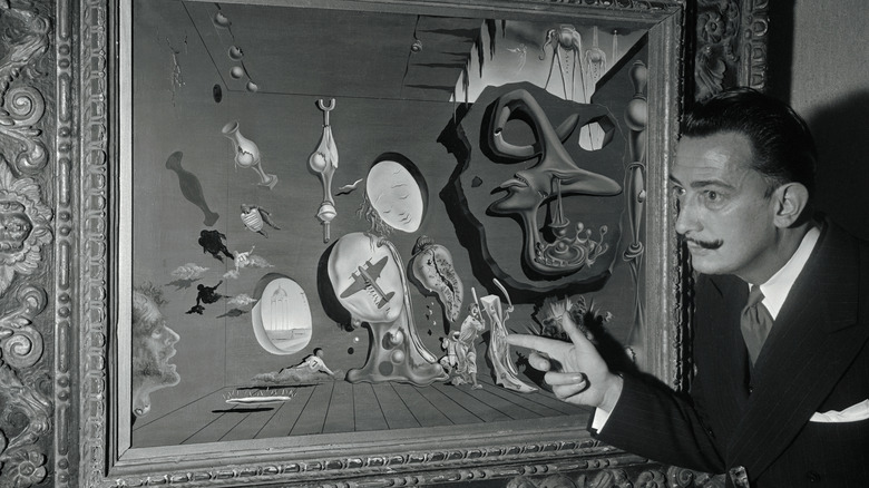 Salvador Dali pointing at one of his paintings