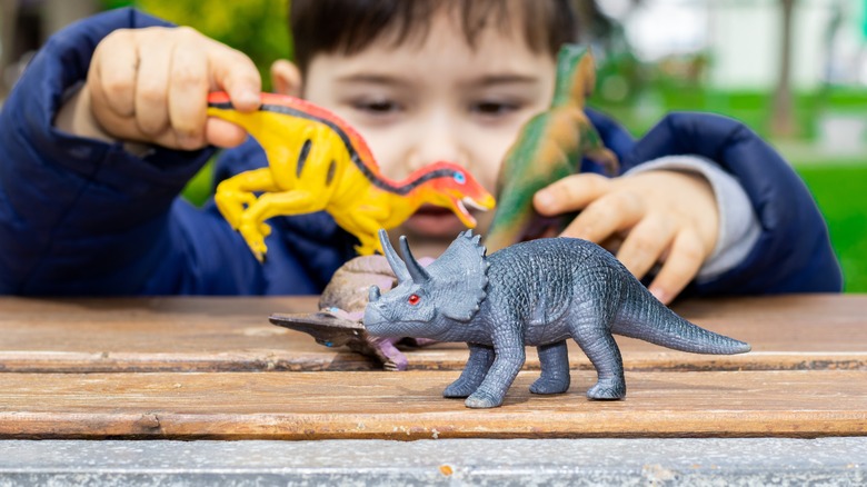 Child playing with dinosaur figures on table