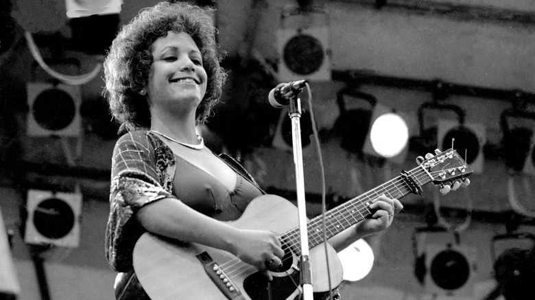 Janis Ian smiling while playing guitar on stage