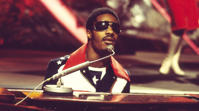 Stevie Wonder singing behind a piano
