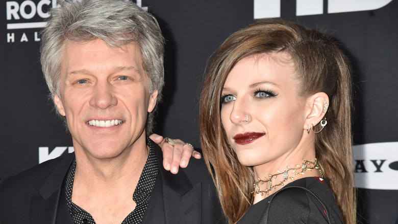 Bon Jovi smiles, daughter leans on him