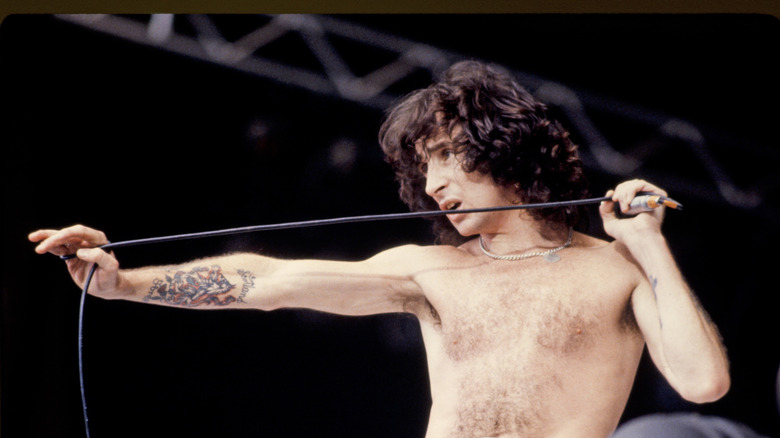bon scott shirtless on stage holding microphone cord