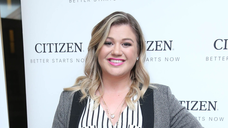 Kelly Clarkson smiling in gray blazer at event