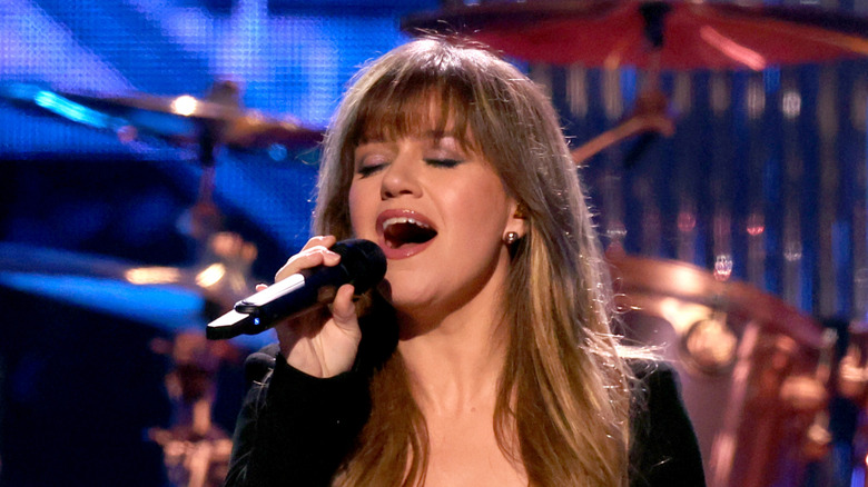 Kelly Clarkson singing on stage with drums in background