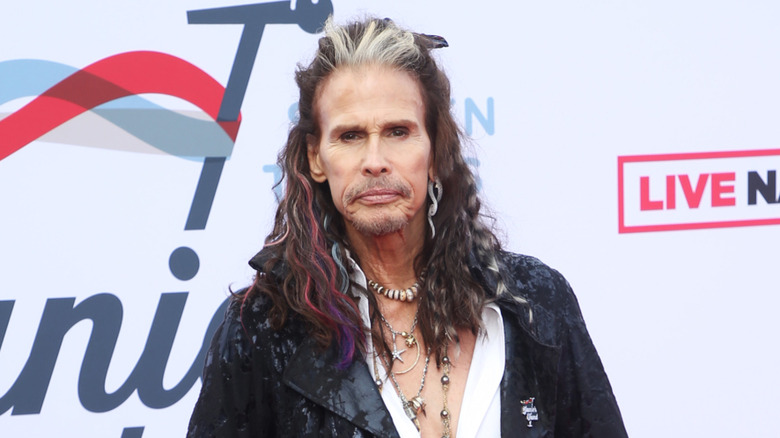 Steven Tyler posing in front of a mutilcolored background in 2022