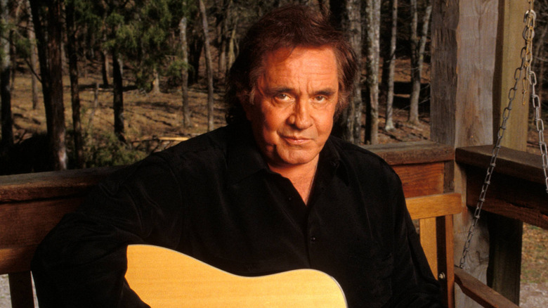 Johnny Cash playing guitar on porch swing in the woods