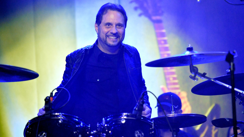 Dave Lombardo sitting behind a drumkit and smiling in 2019