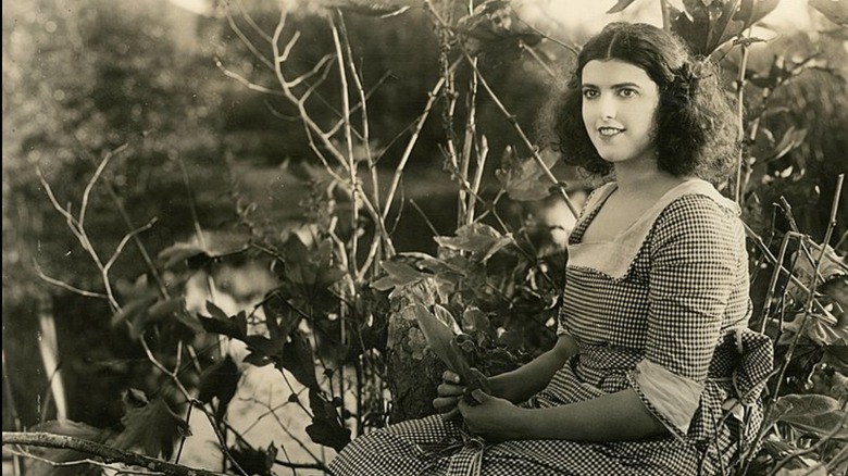 Virginia Rappe sitting near brush