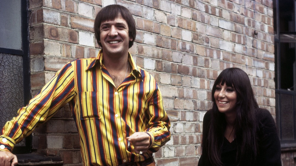 Sonny & Cher pose near a brick wall