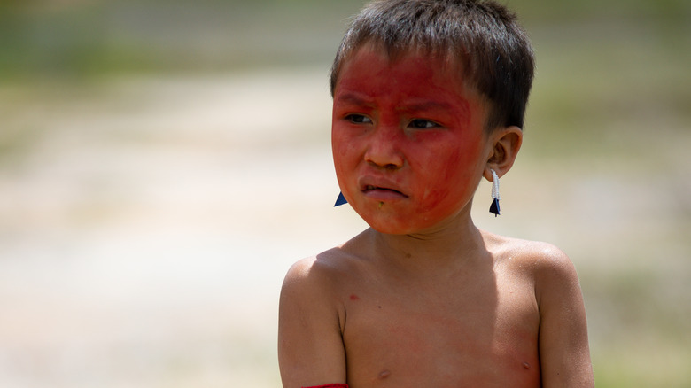 Yanomami boy red face paint earrings