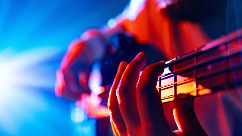 Hands on an electric bass under stage lights