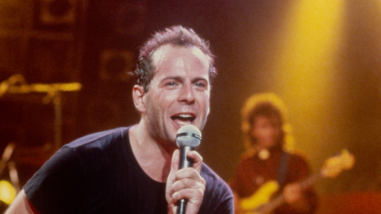 Bruce Willis performing with a band on stage