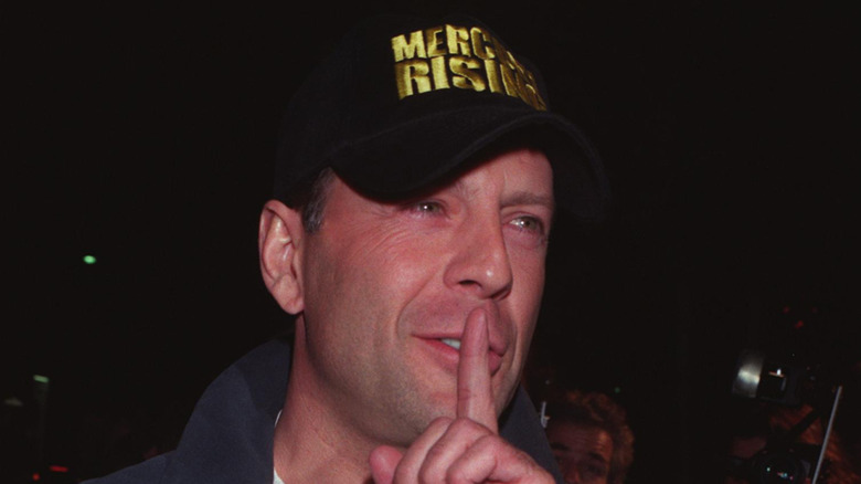 Bruce Willis with finger on lip and wearing Mercury Rising cap