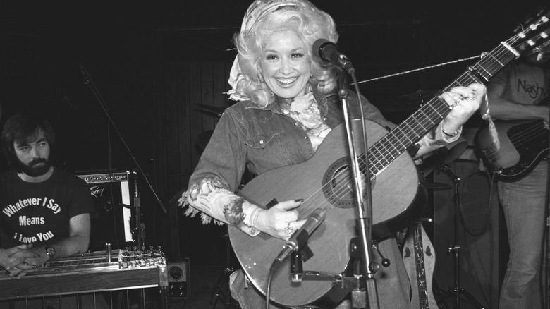 Dolly Parton playing an acoustic guitar onstage