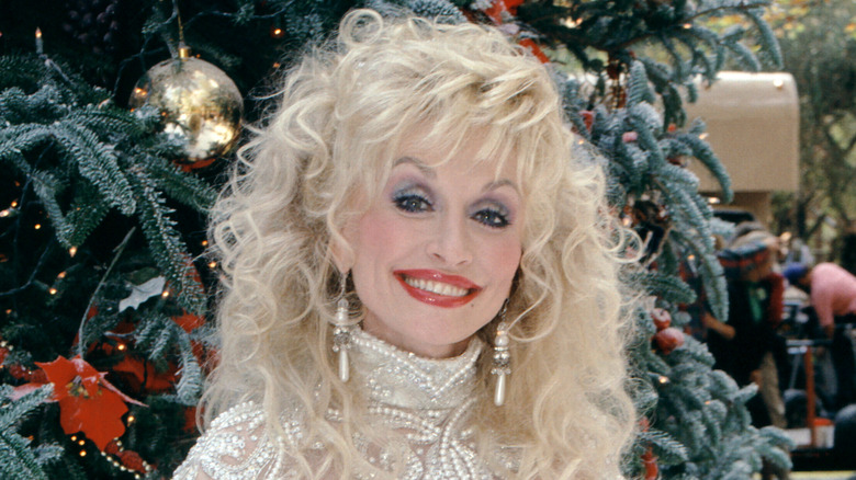 Dolly Parton posing in front of a Christmas tree in 1992