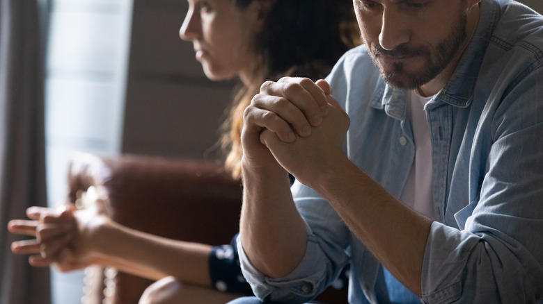 Crop close up of unhappy young couple sit separate have problems in relationship think of breakup or divorce
