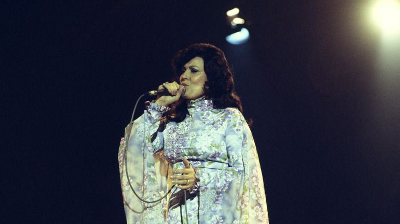 Loretta Lynn in blue floral dress singing on stage