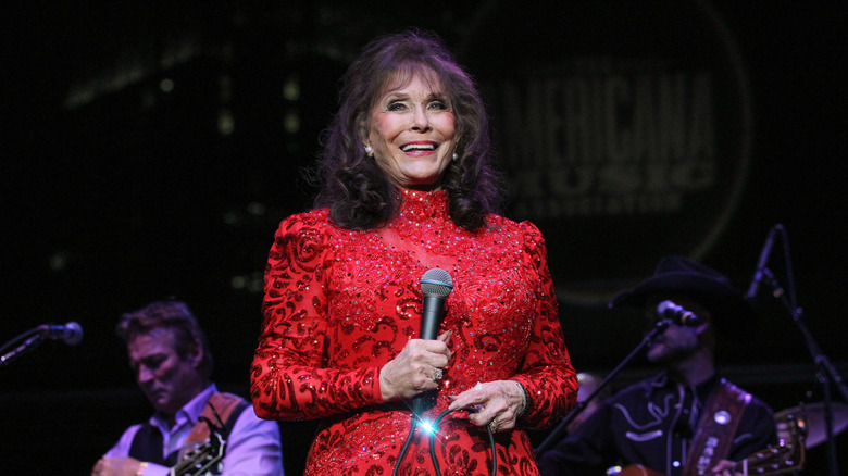 loretta lynn smiling in red dress on stage