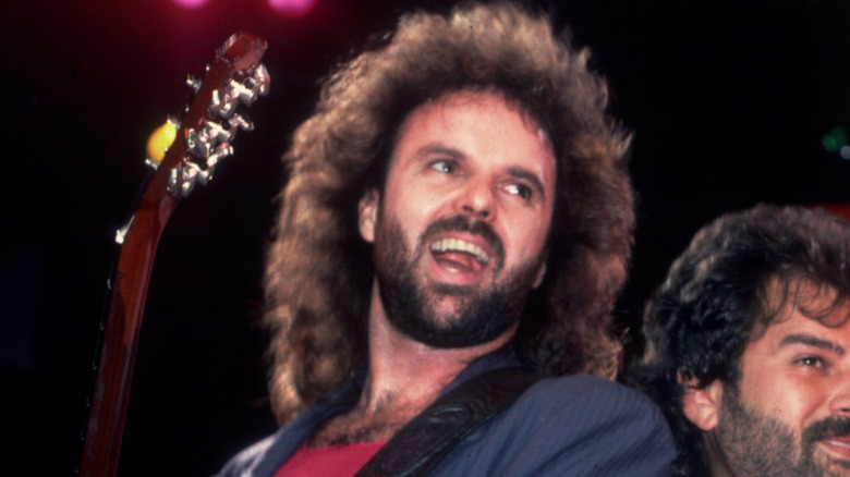 Larry Junstrom smiling and playing bass on stage