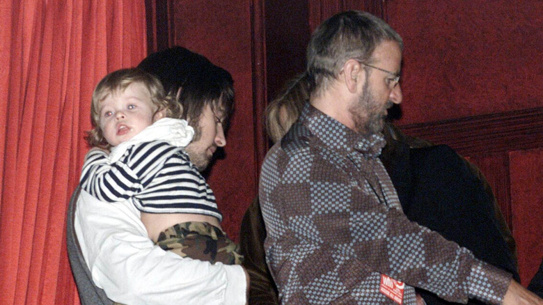 Jason Starkey holds his baby while walking behind Ringo Starr