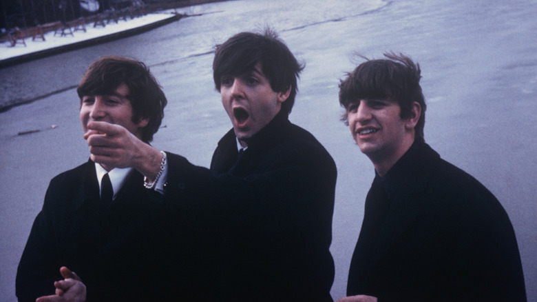 Ringo Starr grimacing behind John Lennon and Paul McCartney smiling