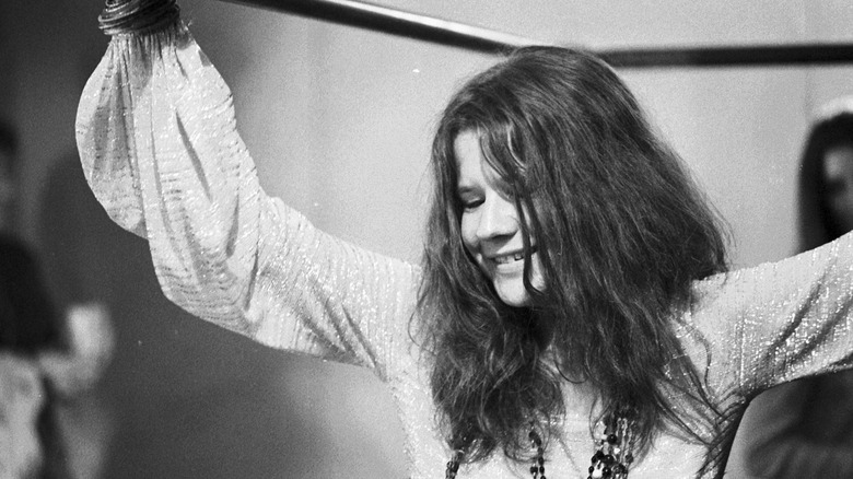 Janis Joplin smiling with arms raised