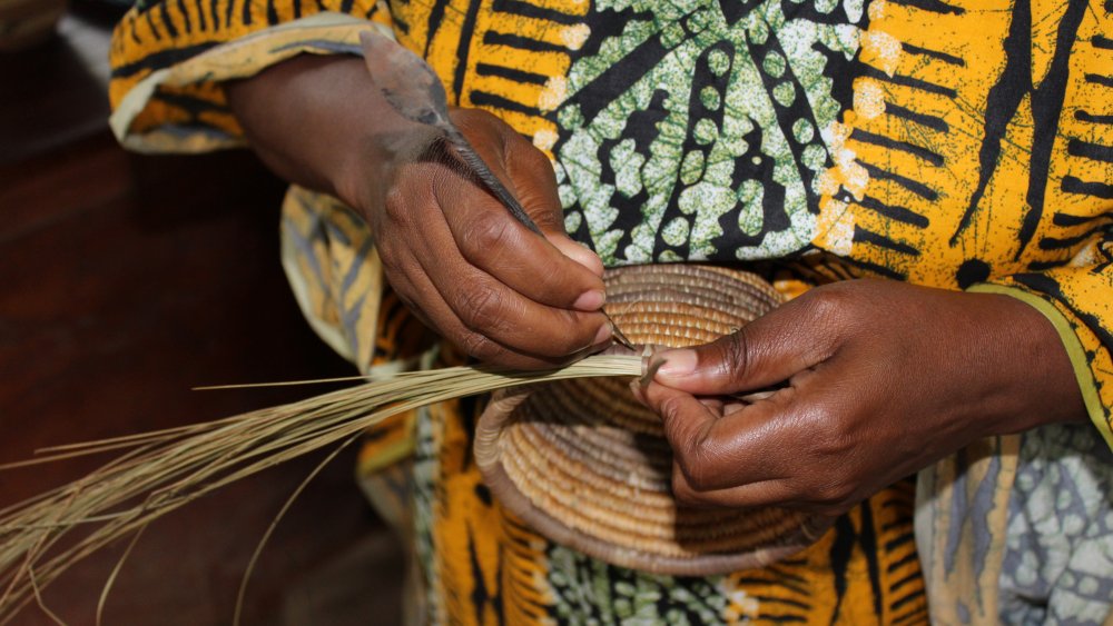 African woman weaving grass into a basket