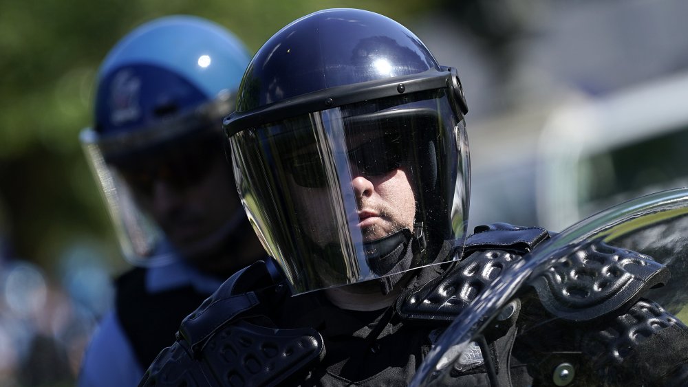 A cop in riot gear surveys the surrounding area