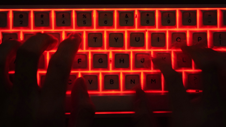 Typing on red illuminated keyboard