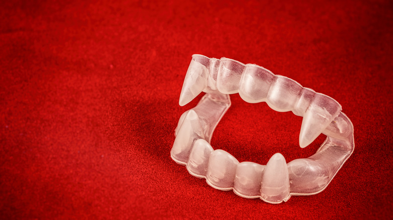Fake vampire teeth, red background