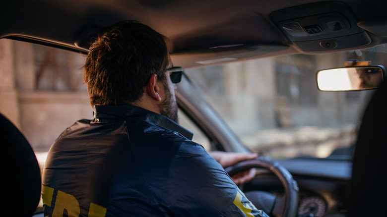 man wearing fbi jacket, driving