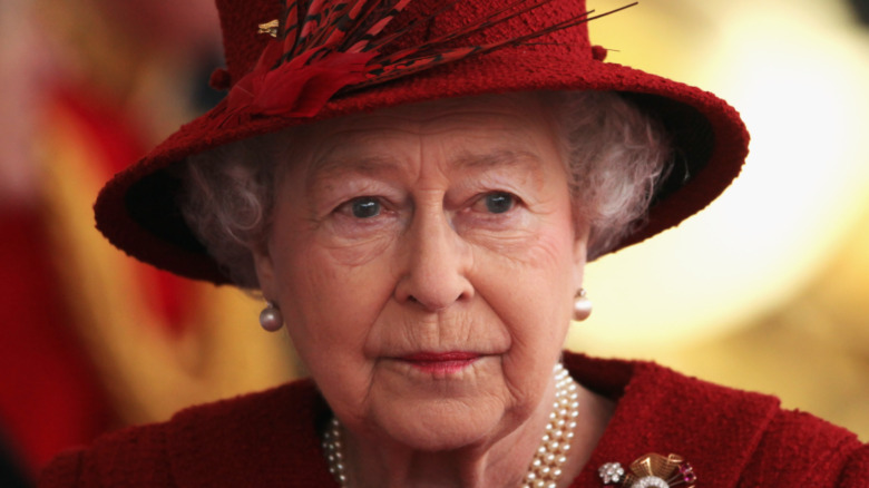 Queen Elizabeth wears red ensemble.