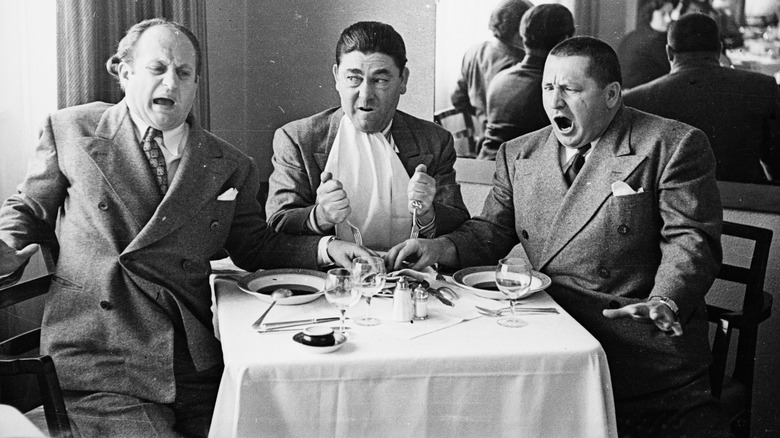 The Three Stooges goofing at a table 
