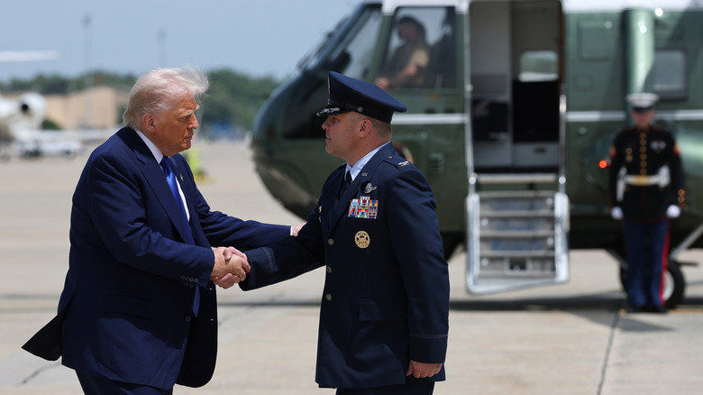 Donald Trump shaking hands with military personnel in front of helicopter