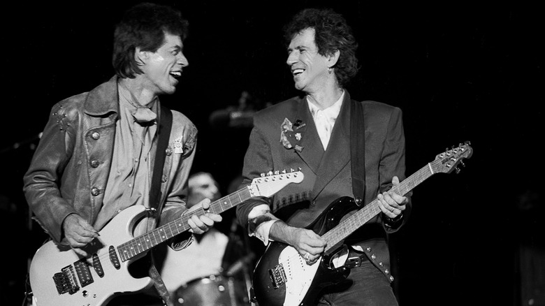 Keith Richards and Mick Jagger smiling at each other while performing on the Steel Wheels tour