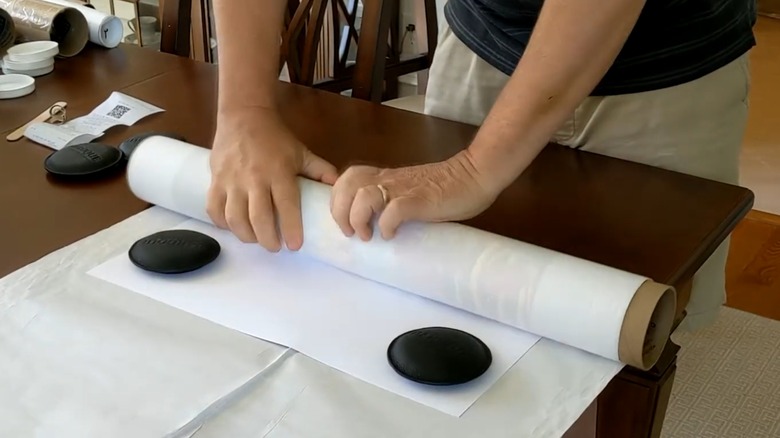 Person unrolling poster with weights on corners