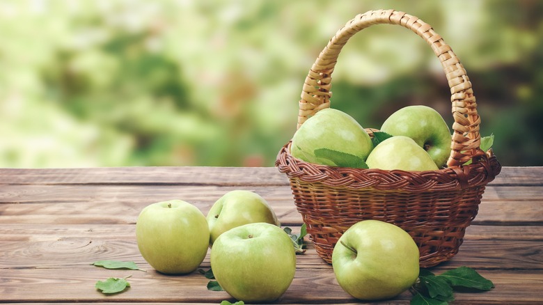 Apples in a basket and on tabletop outdoors