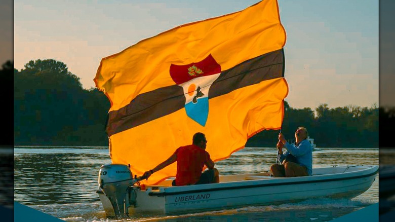 A couple on a boat called Liberland holding the micronation's flag