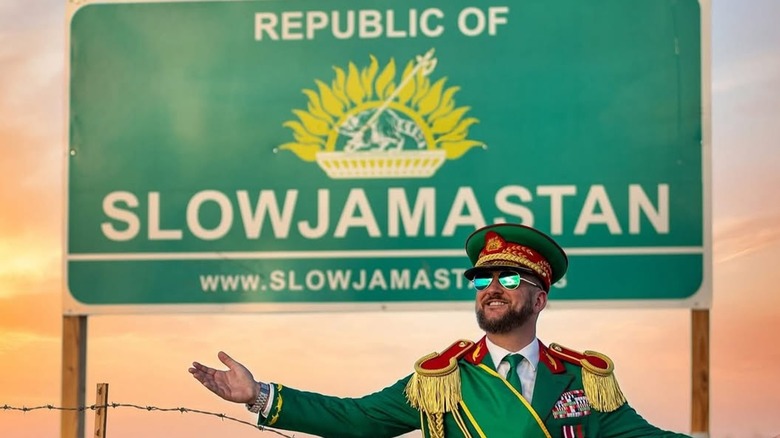 Randy Williams in front of a Welcome to the Republic of Slowjamastan sign