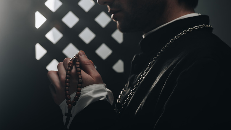 Priest stands in confessional