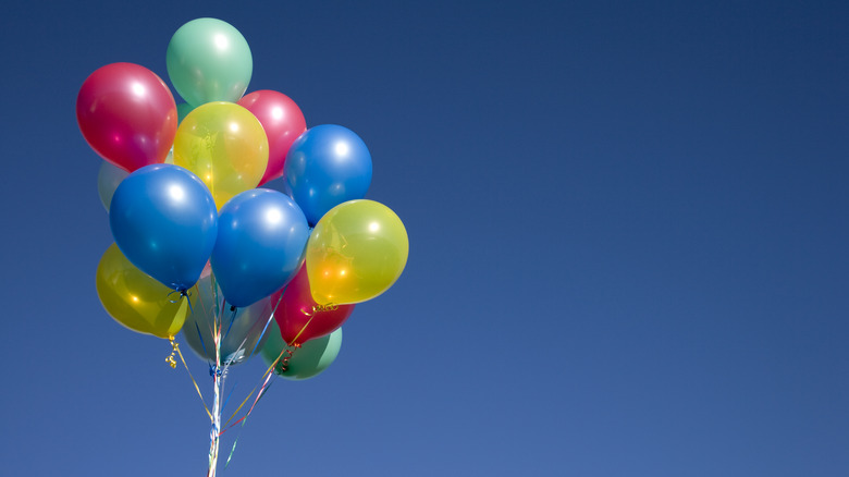 A bunch of colorful helium-filled balloons in front of a blue sky