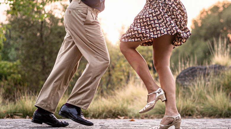 two pairs of legs swing dancing, one in khakis, one in a skirt