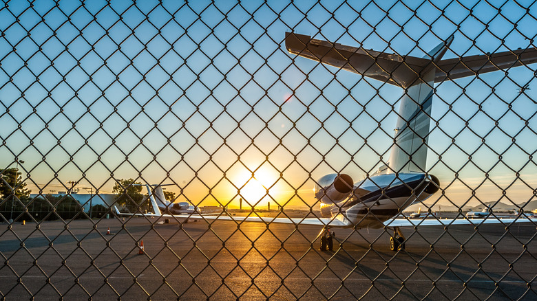 Plane sitting on runway behind chain fence