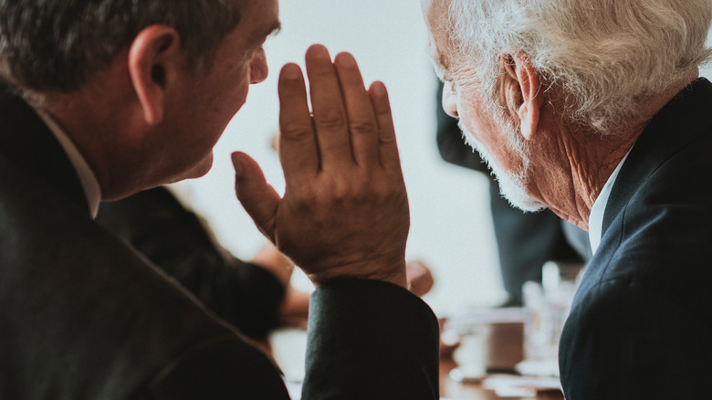 Two men sharing a secret word of importance