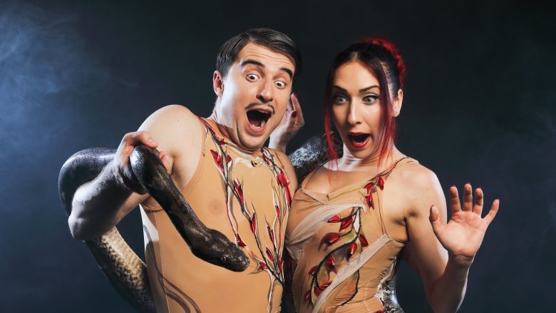 Adam and Eve holding a snake looking scared