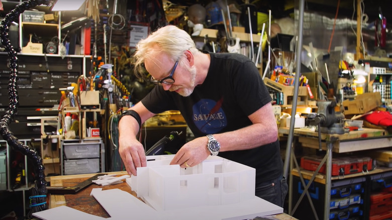 Adam Savage with goatee and glasses in workshop making model of house
