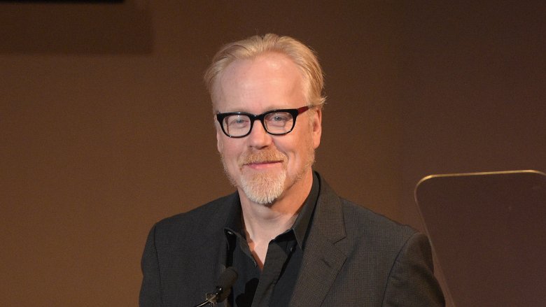 Adam Savage with goatee and glasses smiling in dark suit