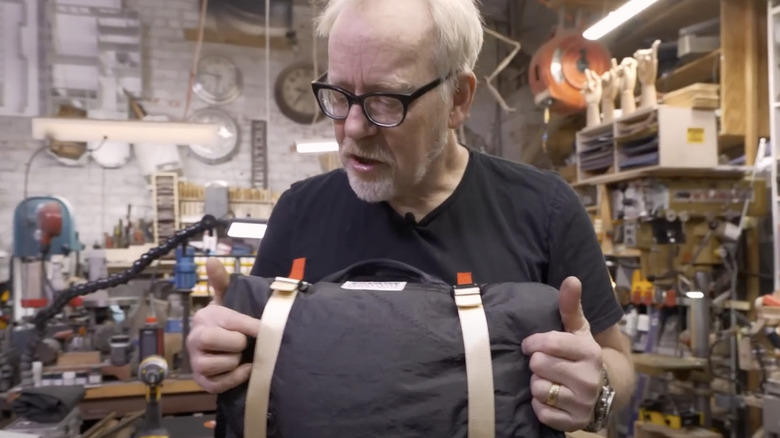 Adam Savage in workshop holding a Savage Industries bag