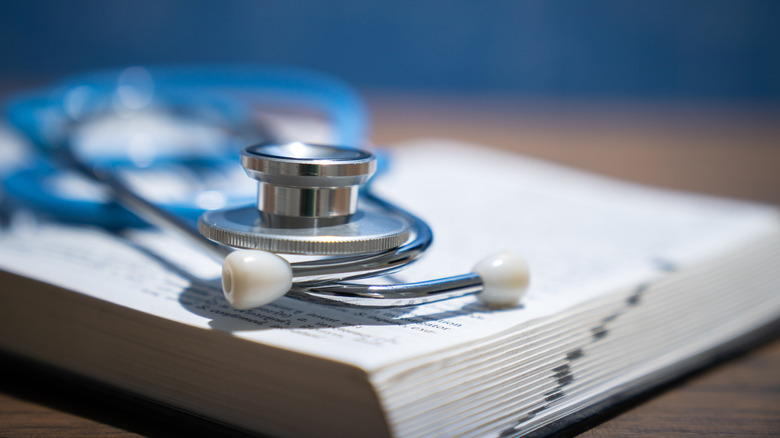 Stethoscope and book on wooden table